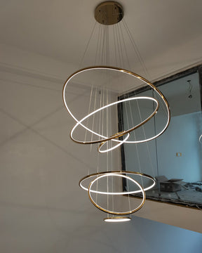 Seven-ring gold chandelier illuminating a newly finished stair void, creating an immediate focal point with minimal visual mass.