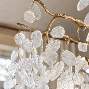 A modern organic branch chandelier with a warm gold metal frame and frosted white crystal petal accents.