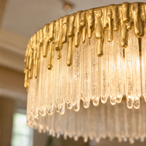 A double-tier chandelier with icicle-style textured crystal drops and a satin warm gold metal band.