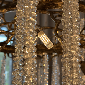 A circular antique gold branch chandelier with cascading crystal bead strands hangs from the ceiling in a lit room.
